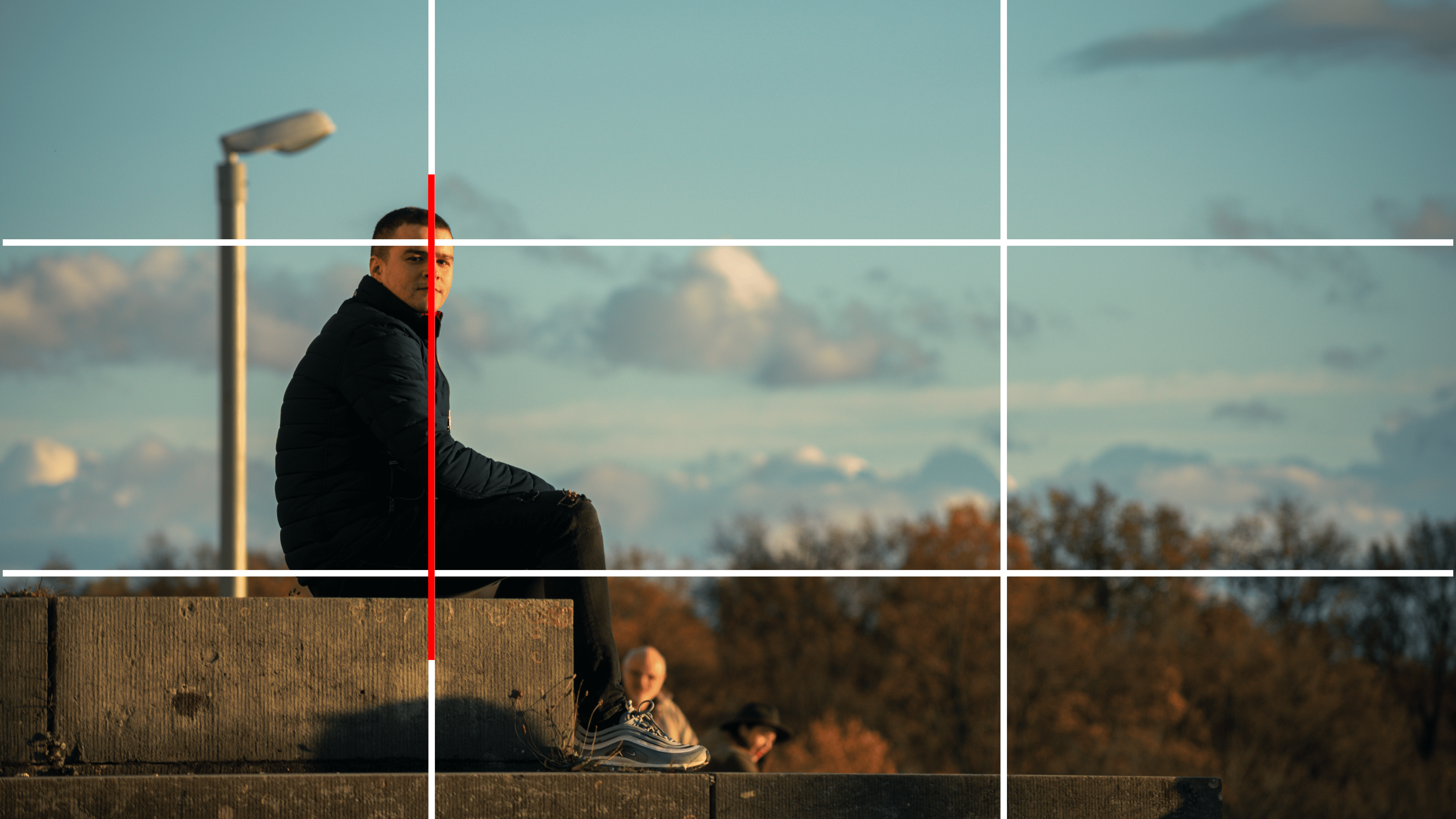A picture of a man sitting on a stone on the left side of the picture with a gridline over the photo showing the example of a “Rule Of Thirds” technique.